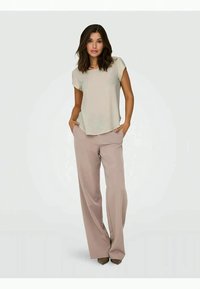 Light beige short-sleeve top paired with loose, light pink trousers. The outfit features a relaxed fit and minimalistic design.