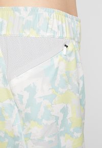 Lätta träningsshorts med ett abstrakt mönster i pastellblått, gult och vitt. Innehåller ett meshnät och en dragkedjeförsedd ficka.