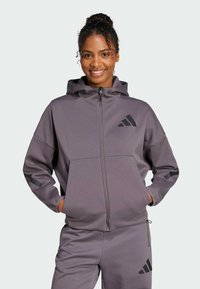 Felpa con cappuccio e zip in tessuto grigio tenue con accenti neri e logo, caratterizzata da una vestibilità relaxed e tasche frontali.