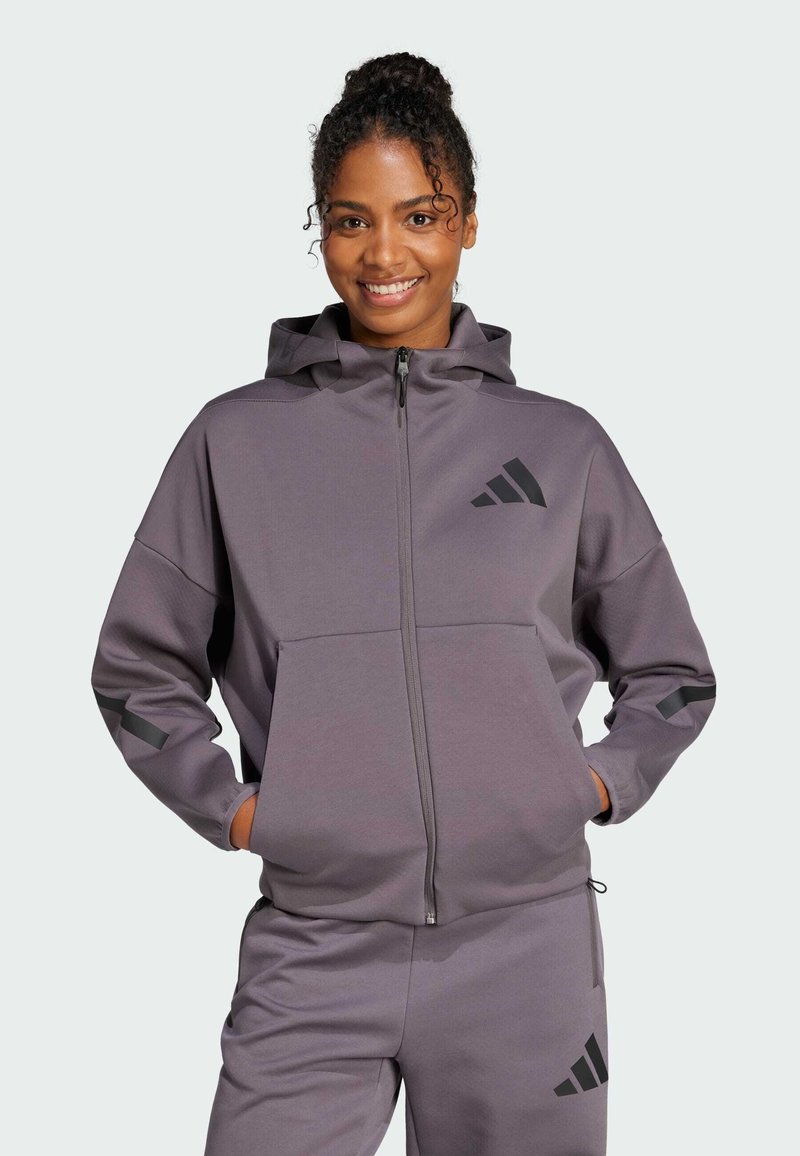 Felpa con cappuccio e zip in tessuto grigio tenue con accenti neri e logo, caratterizzata da una vestibilità relaxed e tasche frontali.