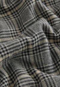 Woven fabric featuring a checkered pattern in black, gray, and yellow, with soft texture and varied striping across the surface.