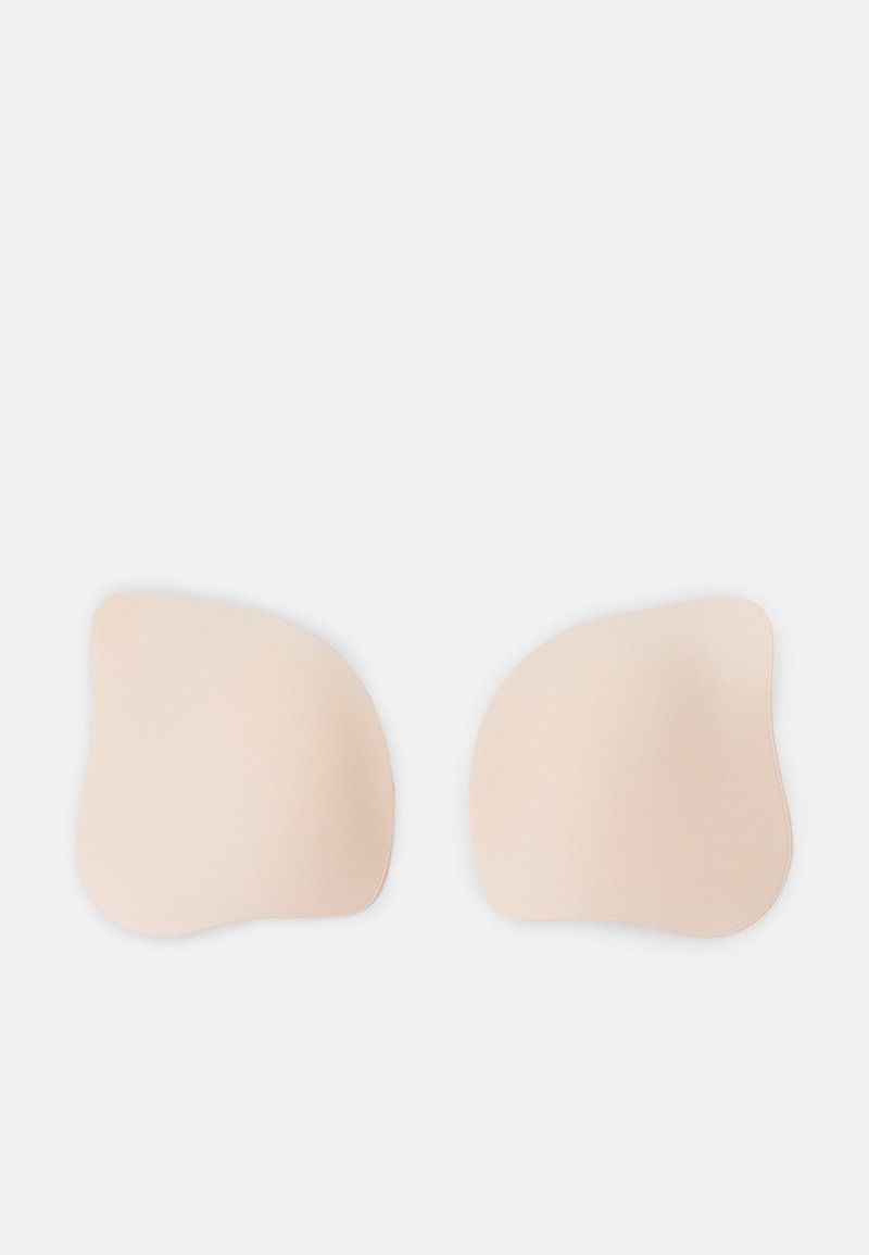 Skin-toned adhesive bra pads in a smooth, irregular shape with rounded edges, designed for discreet support under clothing.
