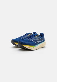 Baskets de sport bleues avec une tige texturée, un logo 'N' en argent bien en vue, une semelle rembourrée et des accents multicolores sur la semelle intermédiaire.