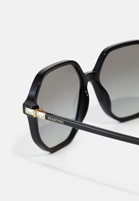 Ochelari de soare octogonali negri cu lentile gri cu efect de degrade, având accesorii aurii și brandul Swarovski pe un design elegant al bradului.