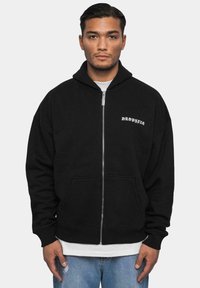 Sweat à capuche noir zippé avec une grande capuche et des poches kangourou. Présente le texte blanc "DROPSIZE" sur le devant. Conçu dans une coupe décontractée.