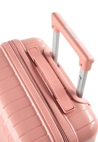 Hartschalenkoffer in pastellrosa mit strukturierter Oberfläche, ausgestattet mit einem teleskopierbaren silbernen Griff und einem Reißverschluss.