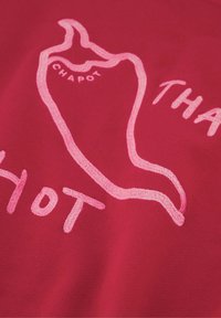 Roter Stoff mit einer Grafik von einer Chilischote in Hellrosa, darunter die Worte "HOT" und der Name "CHAPOT" in verspielter Schrift.