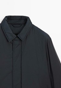 Schwarze gepolsterte Jacke mit einem Kragen, strukturiertem Stoff und Nähdetails. Verfügt über eine lässige Passform und ein minimalistisches Design.