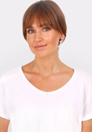 Collier en chaîne en or avec un pendentif en barre verticale, présentant une finition lisse. Porté par-dessus un T-shirt léger blanc avec un décolleté arrondi.