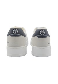 Weiße und marineblaue Sneakers mit einer strukturierten Wildlederferse, glattem weißen Obermaterial und einer Gummisohle. Mit Logo an der Ferse und der Rückseite.