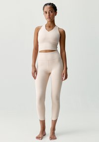 Béžový športový podprsenka a legíny v sade, bezšvový dizajn, priliehavý tvar, jemné výrezy na podprsenke, hladká textúra, dĺžka legín po polovicu lýtok.