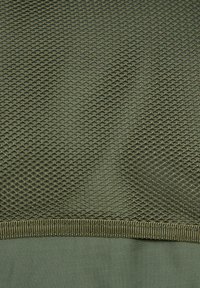Green mesh fabric featuring a diamond pattern with a textured surface, complemented by a smooth, matte green trim at the bottom edge.
