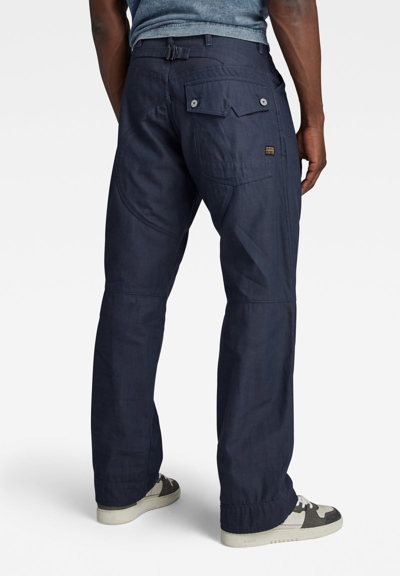 Marineblauwe cargobroek met meerdere zakken, een rechte snit en versterkte knieën. Gemaakt van duurzaam materiaal, met knoop- en ritssluitingen.