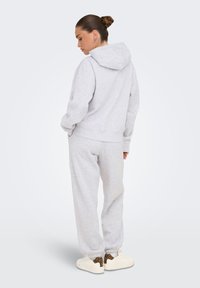 Set di felpa grigia e pantaloni sportivi in tessuto morbido, caratterizzato da una vestibilità comoda, tasche anteriori e polsini a coste. Sneakers con dettagli leopardati.