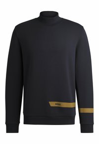 Svart sweatshirt med hög krage, långa ärmar och en gul randdetalj nederst, med en liten logotyp på fållen. Mjuk textur.