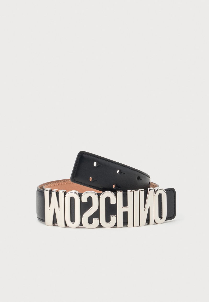Ceinture en cuir noir avec de grandes lettres argentées formant le mot MOSCHINO, pliée sur fond blanc.