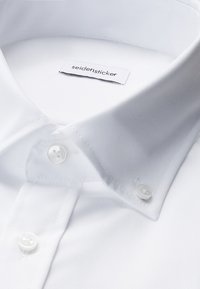 Weißer Hemdkragen mit zwei zugeknöpften Knöpfen, zeigt ein Stoffetikett mit dem Markennamen "seidensticker."