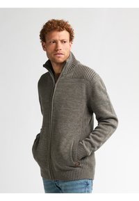 Grauer Strickpullover mit einem hohen Kragen und gerippten Schulterdetails. Das Design verfügt über Fronttaschen und eine glatte Textur.