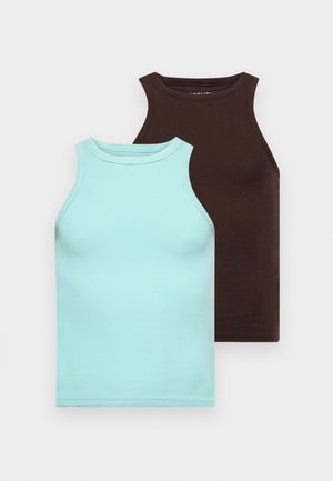 Pruun tank top, kreemid laiad püksid, must pehme kott ühel õlal, ja mustad tossud valgete triipudega.