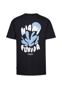 Camiseta negra con texto en negrita en blanco y azul claro que dice "Miami" y "Florida" superpuesto sobre un diseño coral. Estilo clásico de cuello redondo.