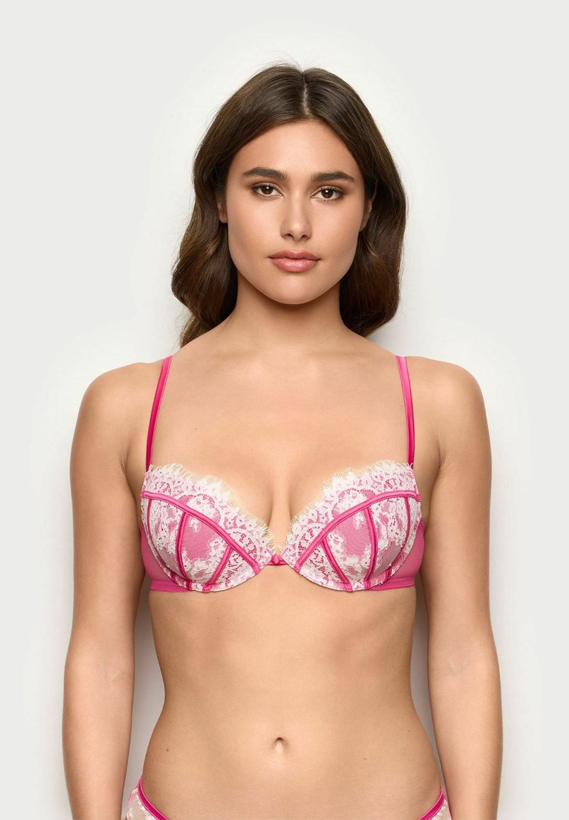 Soutien-gorge en dentelle rose avec un motif floral, des bonnets transparents et des bretelles roses. Présente une bordure en dentelle festonnée le long des bords supérieurs et des coutures audacieuses.