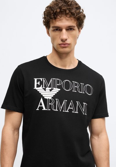 Čierne bavlnené tričko s bielym nápisom "Emporio Armani" a logom, krátkymi rukávmi a okrúhlym výstrihom. Hladká textúra.