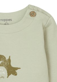 Lichtgroene longsleeve shirt van zachte katoen met een houten knoopdetail op de schouder en een bruine dierenprint.