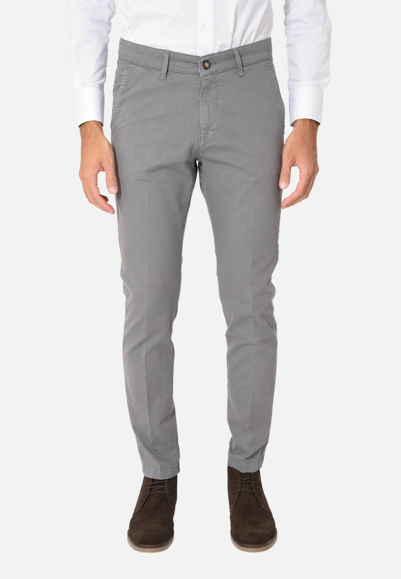 Chinos in cotone grigio chiaro con una vestibilità slim, tasche anteriori, chiusura a un bottone e dettagli di cucitura in vista, abbinati a scarpe marroni scure.