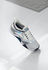 Pantofii sport albi cu accente gri, cu un superior din plasă respirabilă, talpă texturată, model hexagonal și branding Reebok pe lateral și pe limbă.