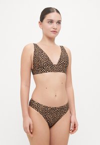 Leopard print bikini featuring a deep V-neckline, wide straps, and matching low-rise bottoms, made from smooth fabric.