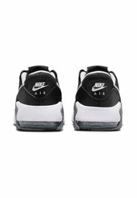 Las zapatillas Nike en blanco y negro presentan un upper de cuero y sintético, una unidad Air visible en el talón y suelas de goma texturizadas.