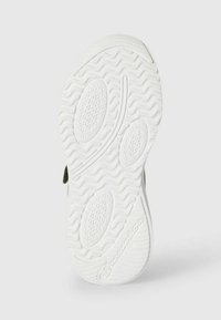 Suola in gomma bianca con una texture ondulata, modelli di presa ovali e un logo ben visibile. Il lato presenta una transizione fluida verso la parte superiore della scarpa.