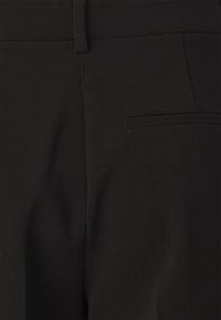 Pantalons noirs avec une texture lisse et élégante, dotés d'une poche latérale et d'un design épuré, adaptés à diverses occasions.