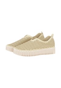 Zapatos beige tipo slip-on con una parte superior de tejido texturizado y suela de goma, que presentan un diseño estriado y orificios de ventilación redondeados en los laterales.