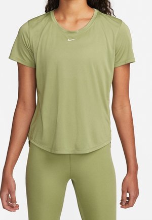 Femme portant un t-shirt de sport à manches courtes vert olive et un legging assorti avec le logo Nike sur la poitrine.