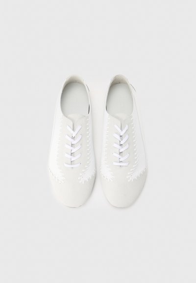 Λευκά δερμάτινα παπούτσια με λευκά κορδόνια, με λείο υλικό, ανάγλυστα ραφές στις άκρες και στρογγυλεμένη μύτη.