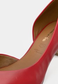 Κόκκινο δερμάτινο ψηλοτάκουνο παπούτσι με λεία υφή, στρογγυλή μύτη και μεσαίο πάτο σε καφέ απόχρωση που περιλαμβάνει διακριτική σήμανση και λεπτομέρειες ενίσχυσης.