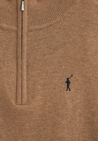 Brauner Strickpullover mit Viertel-Reißverschluss, mit geripptem Kragen und einer dunkelblauen bestickten Figur auf der linken Seite. Weicher, strukturierter Stoff.