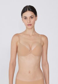 Sostén push-up nude con tirantes delgados ajustables, copas sin costuras y una textura suave. Presenta un diseño clásico con aros para mayor soporte.