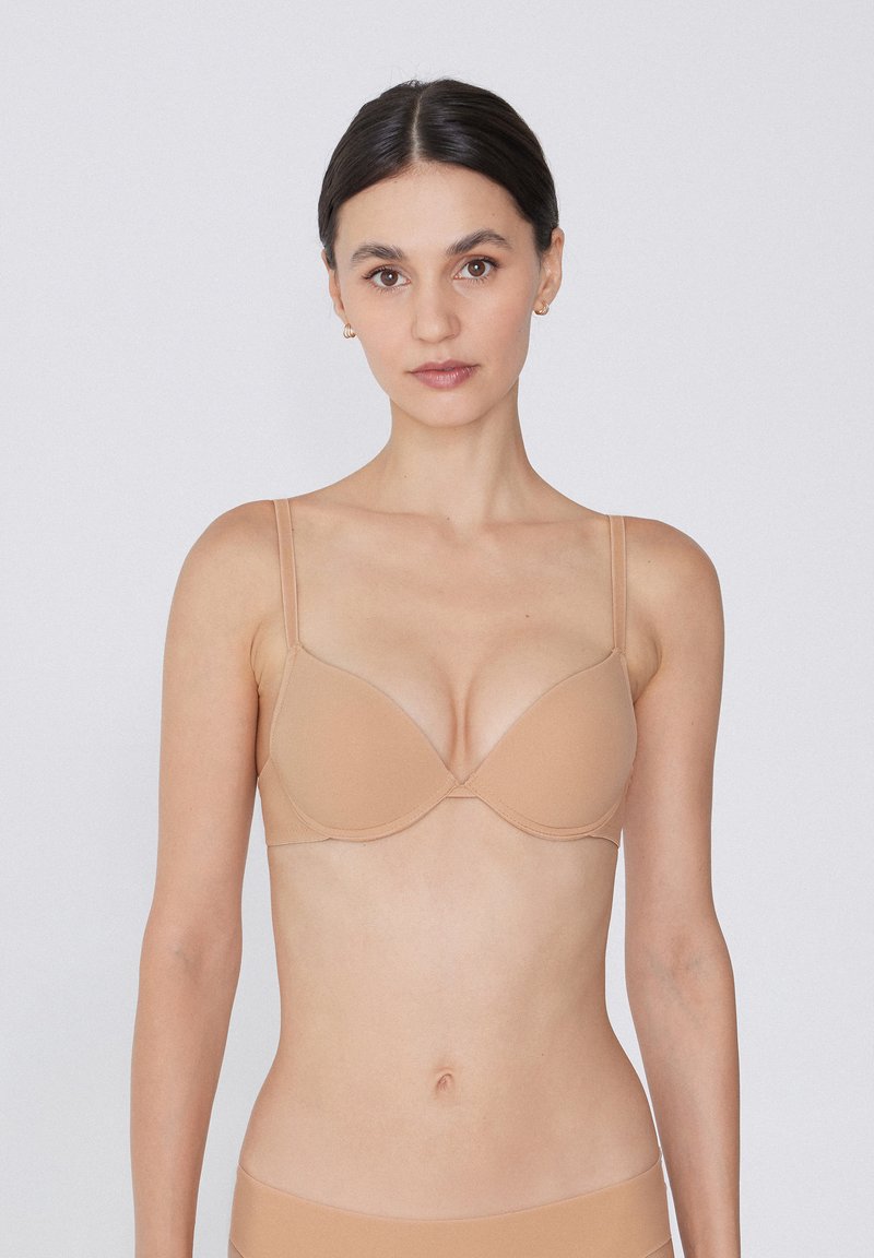 Sostén push-up nude con tirantes delgados ajustables, copas sin costuras y una textura suave. Presenta un diseño clásico con aros para mayor soporte.