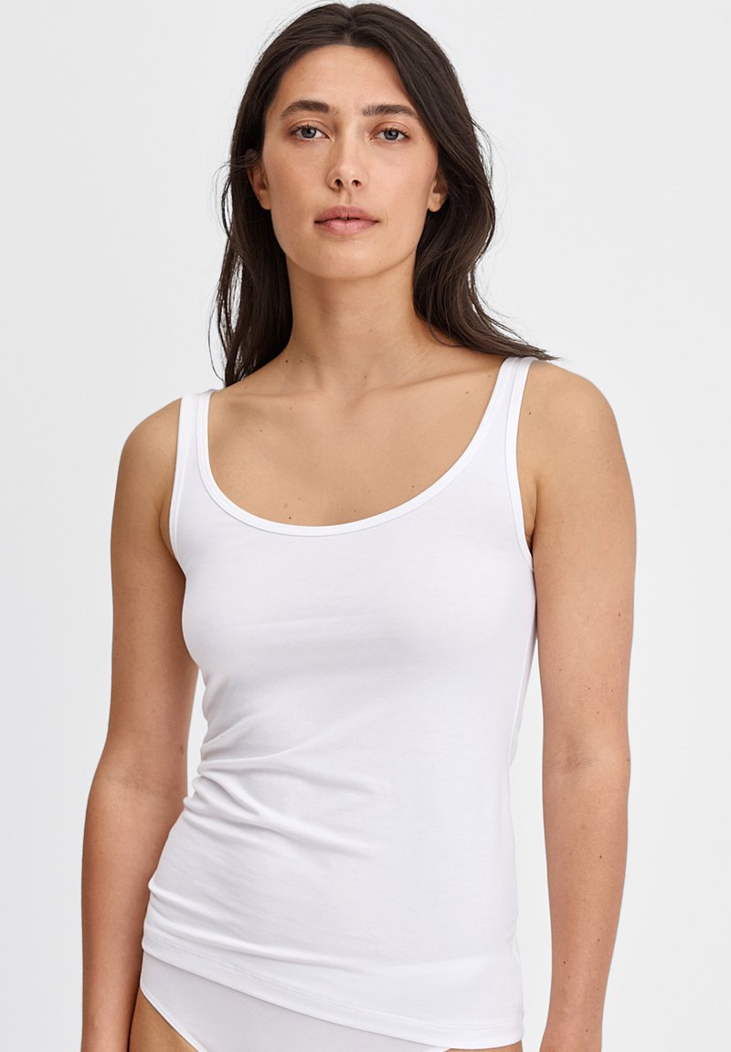 Witte tanktop van zacht katoen, met dunne straps en een ronde halslijn. Het ontwerp is eenvoudig en heeft een nauwsluitende pasvorm.
