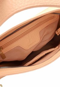 Tan värvi nahast käsikoti sisemus, millel on tõmblukuga tasku, kangast vooder ja avatud põhiosaga õmmeldud detailidega.