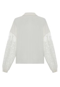 White shirt with a classic collar and long sleeves, featuring sheer lace patterns on the sleeves and a smooth texture on the body.
