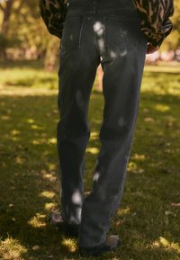 Jeans de mezclilla gris con un corte relajado, que cuentan con bolsillos traseros y un ligero desgaste. La tela tiene una textura suave, combinados con zapatos oscuros.