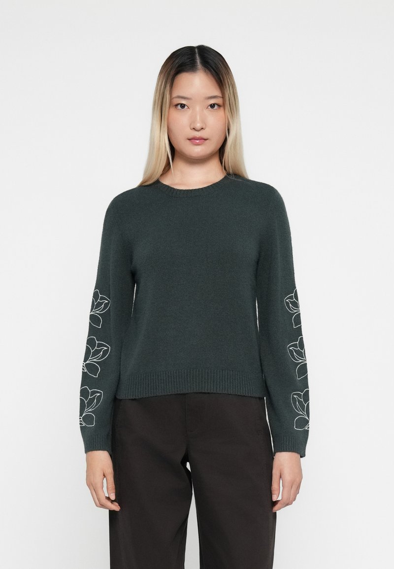 Pull en tricot vert foncé avec un col rond, décoré de broderies florales blanches sur les manches et de bords-côtes aux poignets et à l'ourlet.