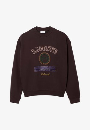 Donkerbruine sweatshirt met voorzijde bedrukte tekst in verschillende kleuren, waaronder "LACOSTE", "TENNIS" en "HERITAGE." Geribbelde mouwen en halslijn.