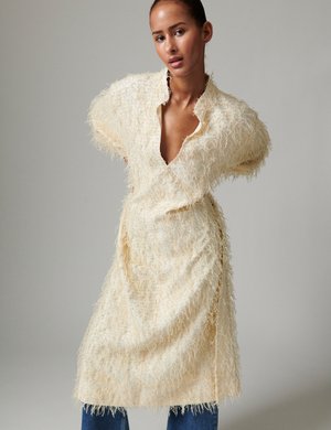 Strukturiertes cremefarbenes Kleid mit tiefem V-Ausschnitt und lockeren, kurzen Ärmeln. Verfügt über ein ausgefranstes Fasern-Design und eine entspannte Silhouette. Wird über Denim getragen.