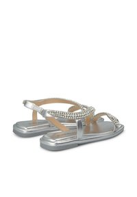 Sandali piatti in argento con cinturini incrociati decorati da strass. Finitura metallizzata liscia, soletta imbottita e altezza del tacco minimale.
