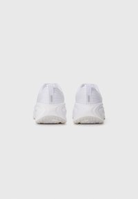 Pair of white athletic shoes with textured soles viewed from the back on a plain white background.