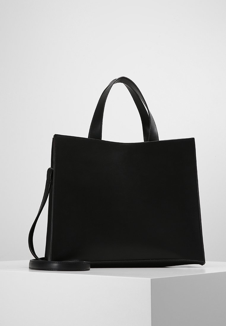 Czarna, strukturalna torba typu tote wykonana z gładkiej skóry. Posiada dwa uchwyty na górze oraz odczepiany pasek na ramię. Minimalistyczny design, bez widocznych elementów metalowych.